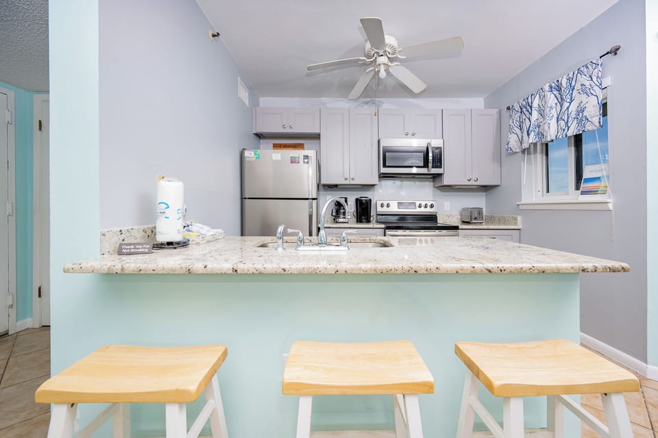 The kitchen features sleek stainless appliances, granite countertops, and a cozy breakfast bar perfect for casual dining