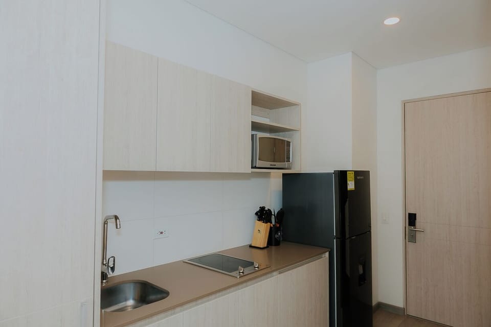 Cocina equipada con estufa, fregadero, microondas y utensilios básicos