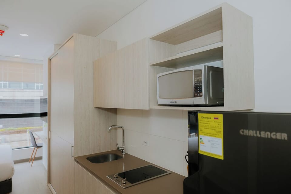 Cocina equipada con nevera, microondas, estufa y muebles funcionales.