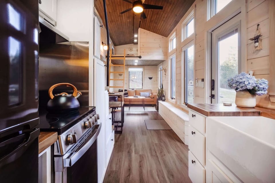 The kitchen with farmhouse sink, butcher block counter tops, full stove / oven and apartment-sized fridge + freezer.