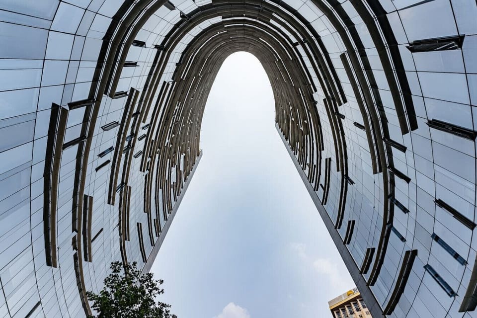 A striking, curved skyscraper with reflective glass panels frames the sky.