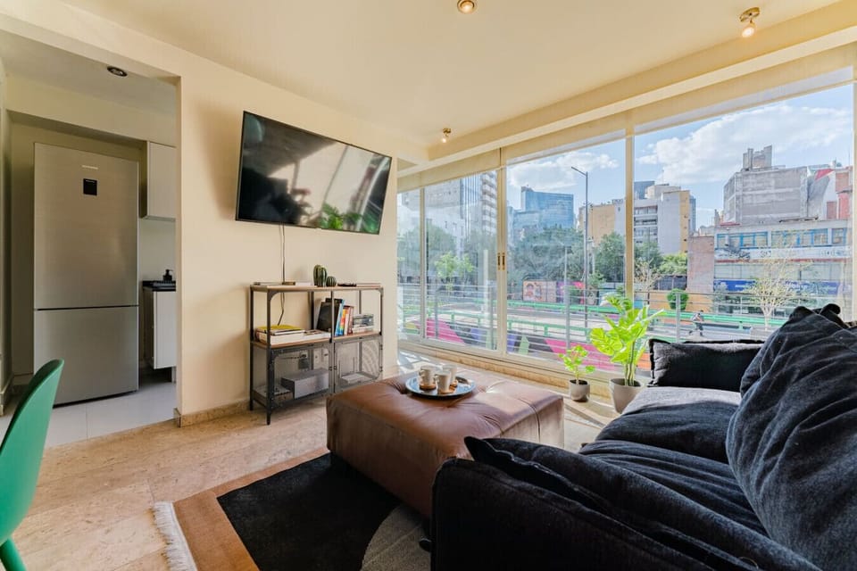 A bright, spacious living room with large windows showcasing city views.