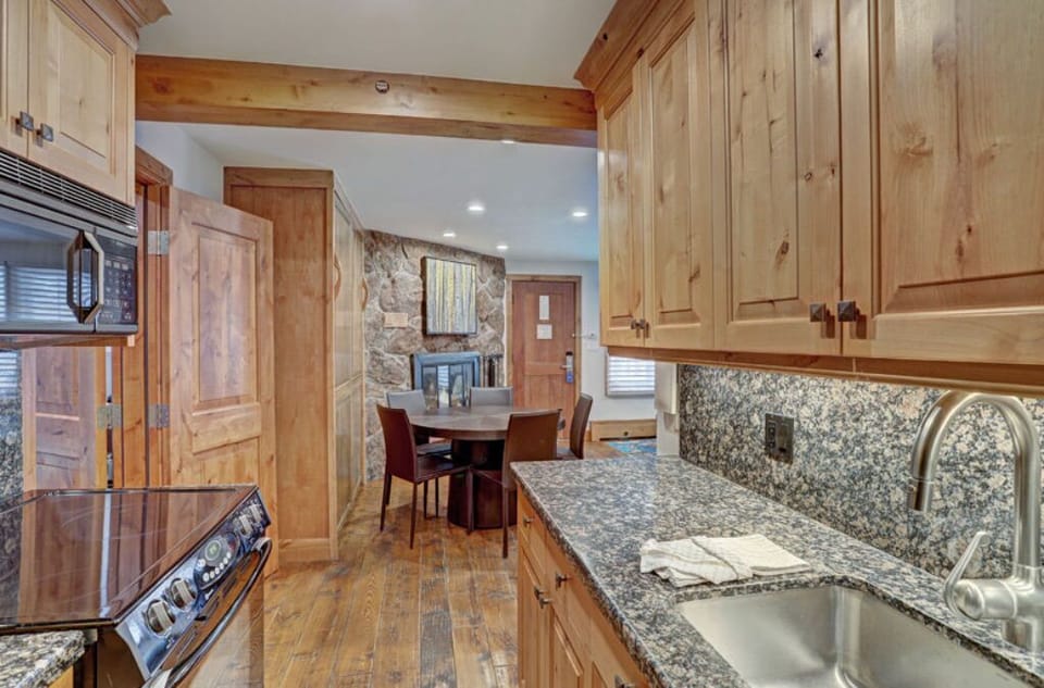 Conveniently designed kitchen with granite countertops and stainless steel sink, seamlessly connecting to the dining area. Perfect for entertaining guests while preparing meals, offering a comfortable and practical space.