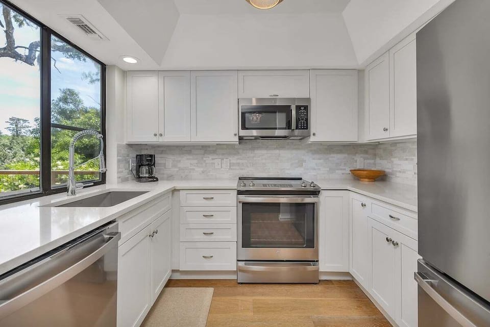 Kitchen with white cabinets, stainless appliances, and large window