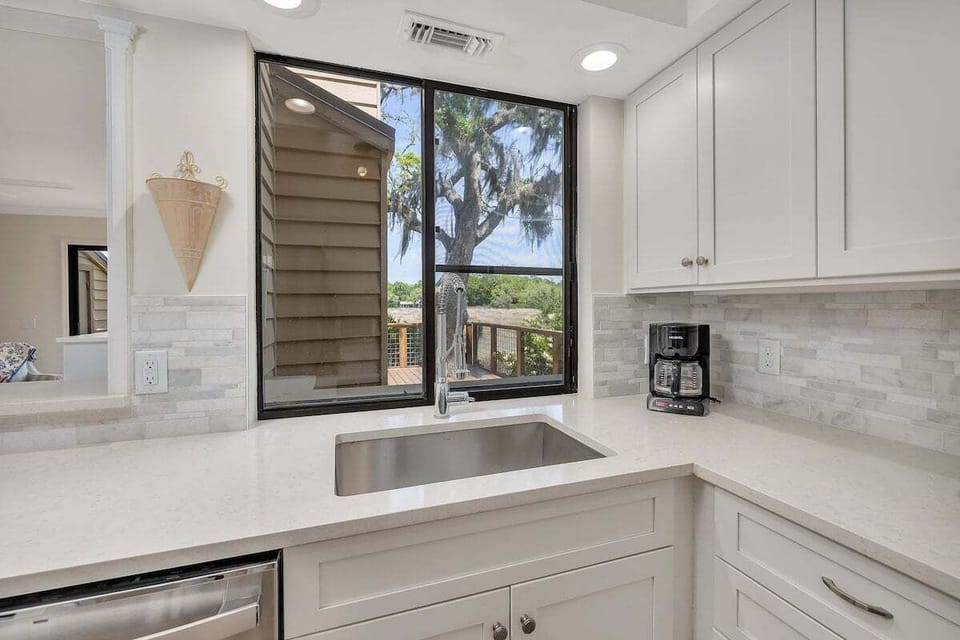 Kitchen with white cabinets, stainless sink, and large window