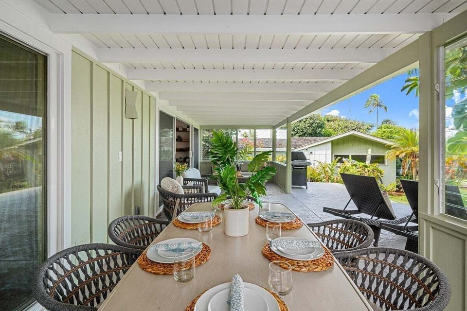 Enjoy alfresco meals on a breezy lanai featuring a stylish dining setup and greenery.