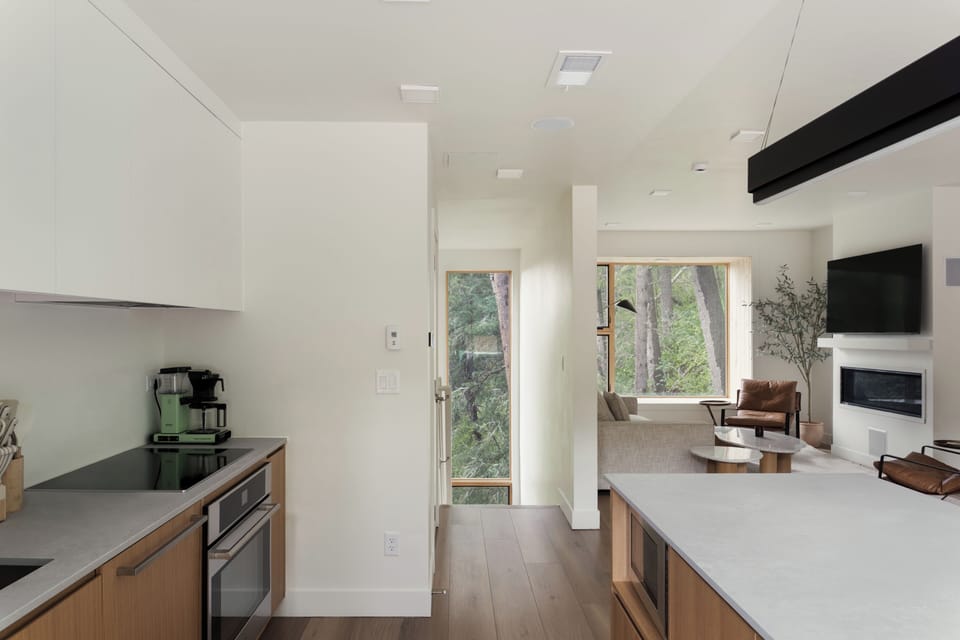 Sleek kitchen with island seating and wide glass doors opening to the deck.
