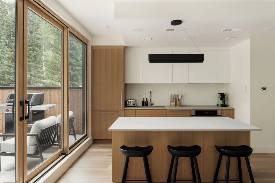 Sleek kitchen with island seating and wide glass doors opening to the deck.