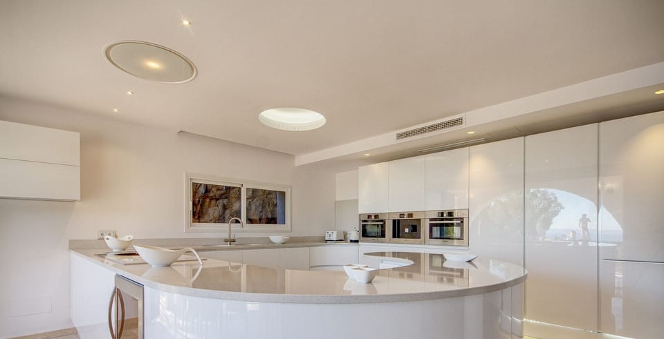 White designer kitchen with large central island at Villa Ocean View, Portals Nous. Modern, bright and fully equipped space.