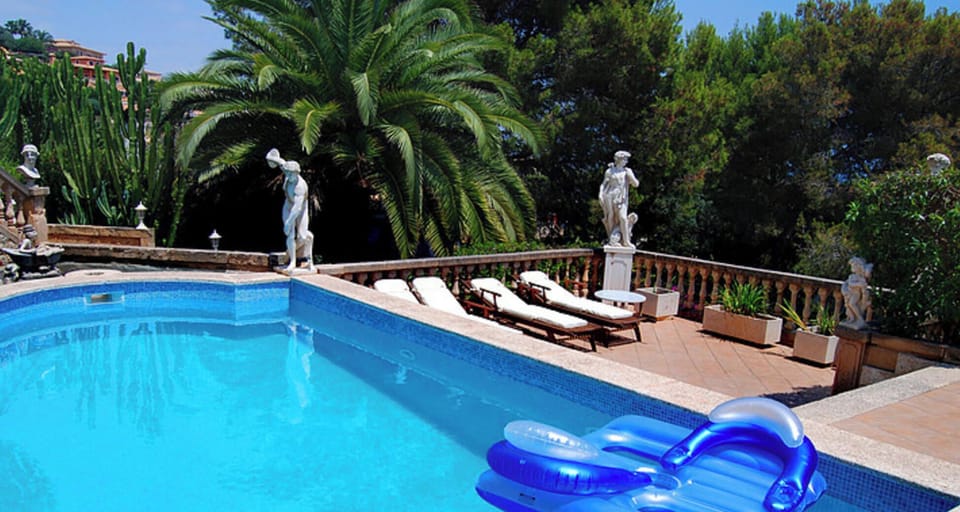 Private pool with classical terrace, decorative statues and sun loungers at Villa Ocean View.