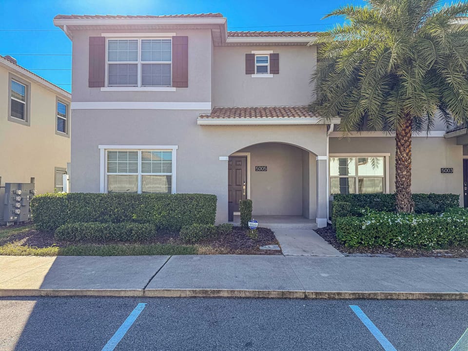 Exterior view of the townhouse with lush landscaping and parking.