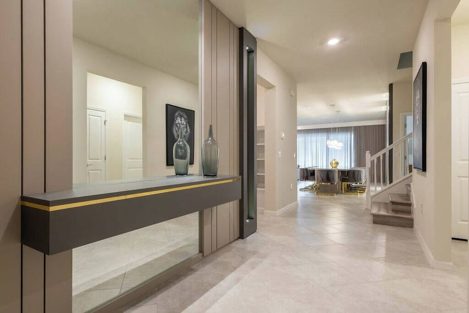 Welcome to a stylish hallway with sleek gray walls and a modern console table, adding sophistication. Natural light pours in through large windows, inviting you to discover the cozy living area ahead. Enjoy your stay!