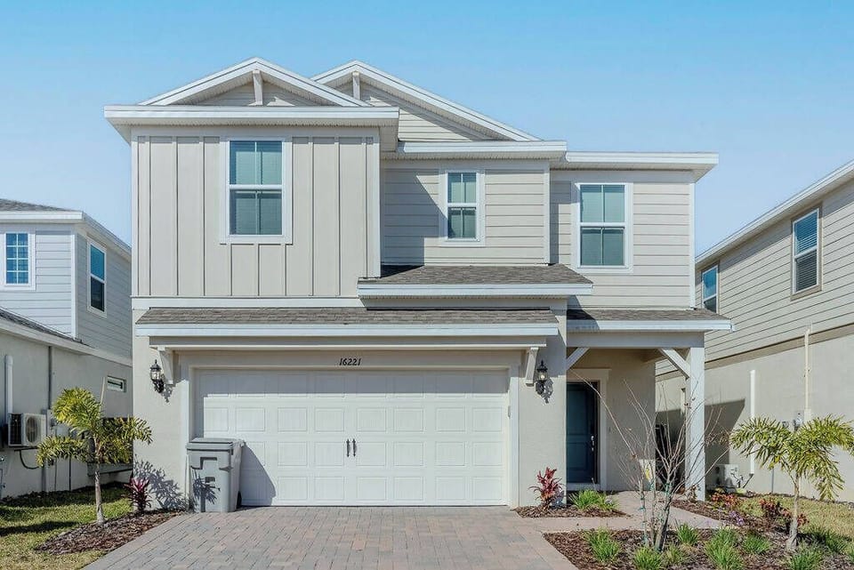 Experience the charm of this light gray home with crisp white accents and a welcoming front porch surrounded by lush greenery. The spacious layout and modern design promise a delightful stay for every guest.