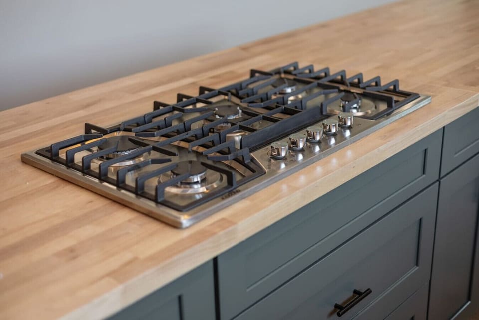 Five-burner gas cooktop built into a butcher block island for easy meals.