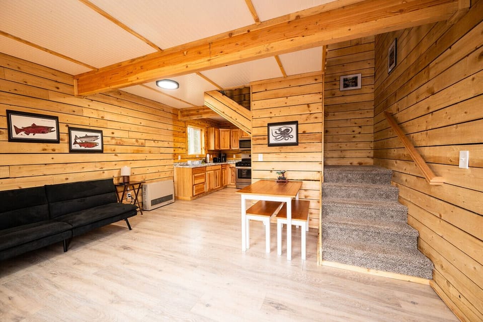 Open cabin layout with cozy seating, full kitchen, dining area, and easy access to the loft via the central staircase.