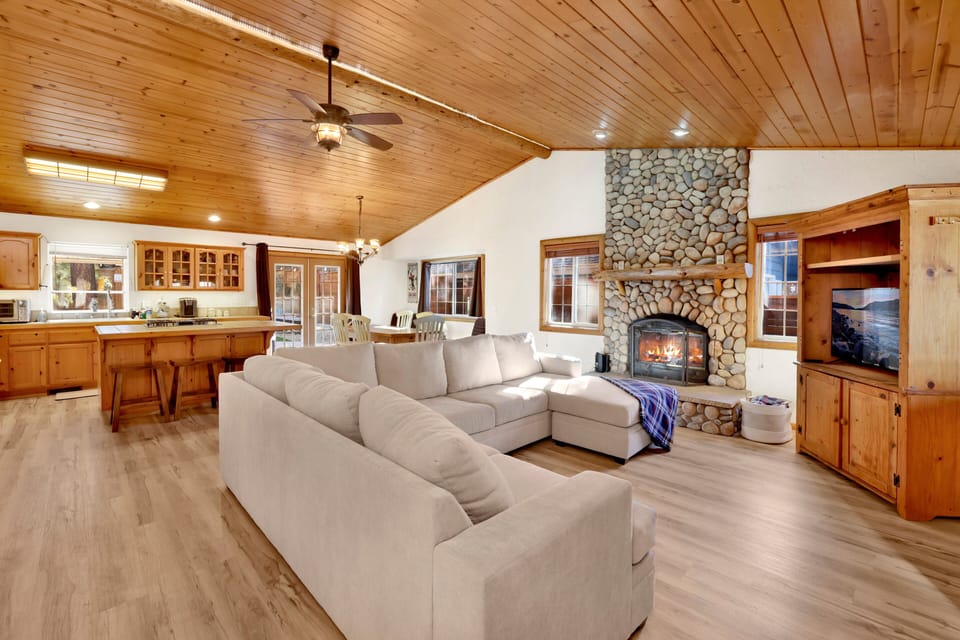 Cozy mountain living room with a stone fireplace, comfy seating, and smart TV—perfect for relaxing evenings, movie nights, and warm cabin vibes after outdoor adventures.