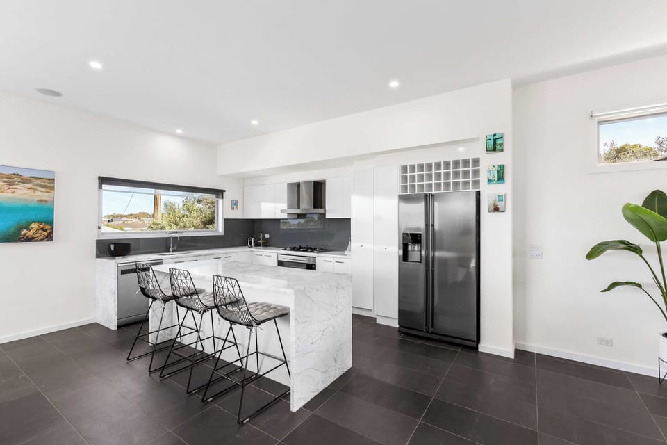 The kitchen showcases a stunning marble waterfall island bench, perfect for entertaining or informal meals