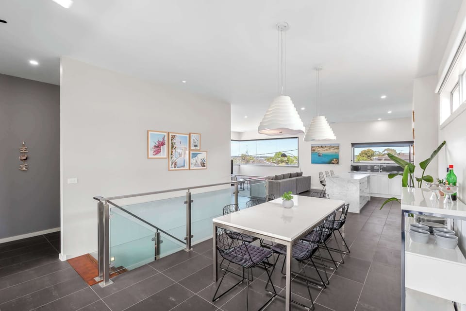 Abundant natural light sweeps through the open plan upper level, with open plan kitchen, living, dining, powder room, and an east-facing deck