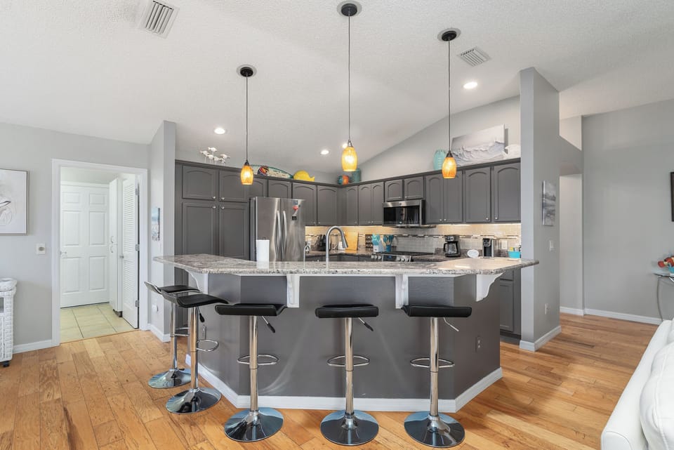 Kitchen with 5 bar stools. Laundry room to the left