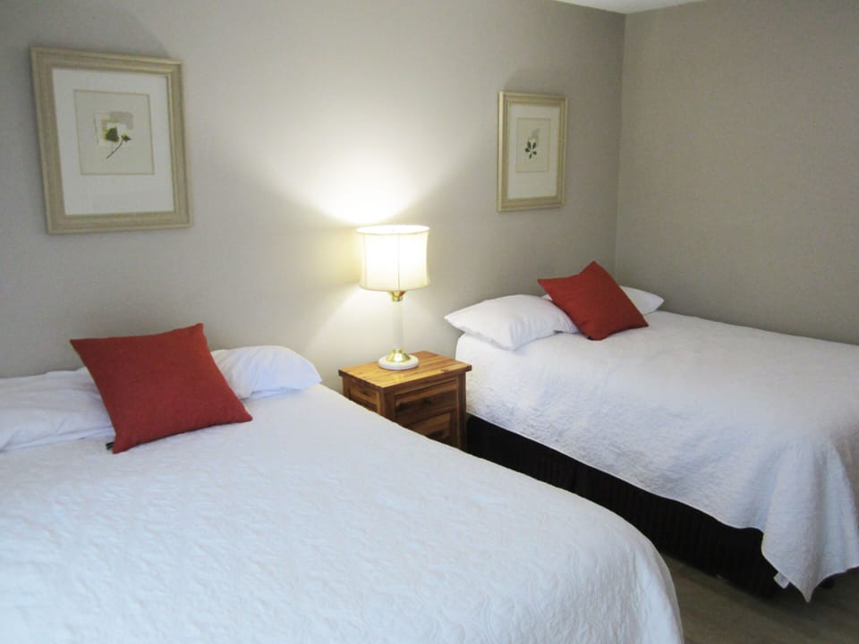 Your peaceful twin bedroom awaits, with crisp white linens, soft lighting, and warm touches of color that invite restful sleep after a day of exploring.