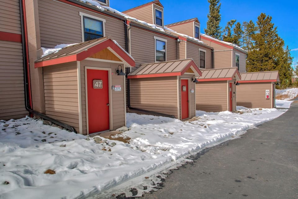 Multi-unit property building featuring distinctive red doors and snow-covered grounds in a peaceful winter setting.