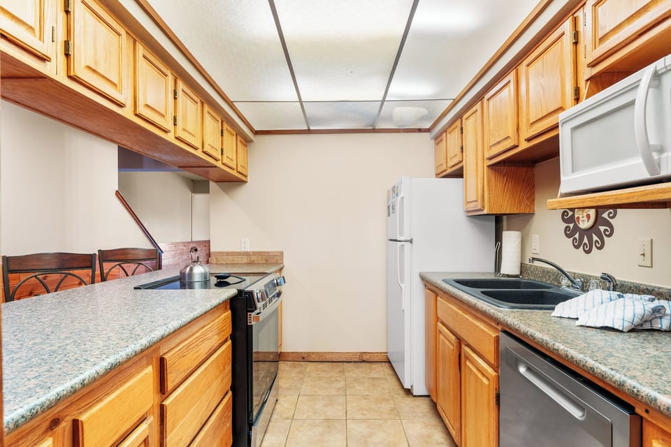 Your fully equipped kitchen features warm wood cabinets, granite counters, and modern appliances - perfect for preparing memorable meals during your stay.