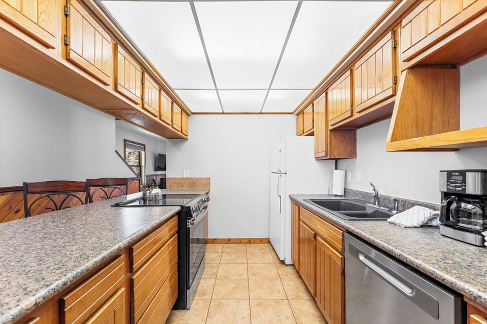 Your fully equipped kitchen awaits with granite countertops, rich wood cabinetry, and modern appliances for creating memorable meals together.