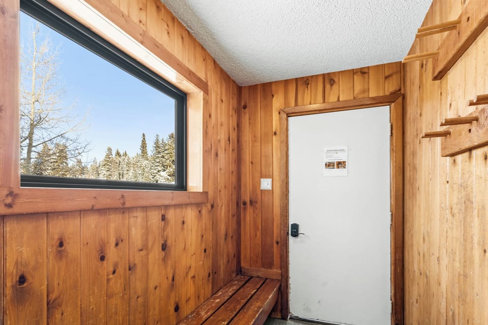 Cozy wood-paneled changing area with snowy forest views through the window, perfect for warming up after winter adventures.