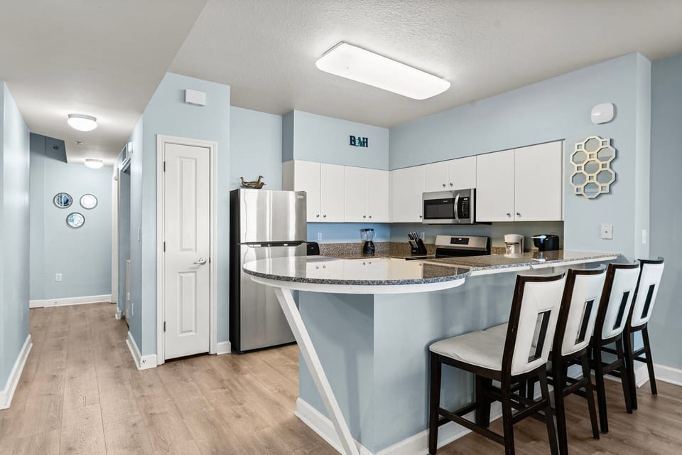 Modern kitchen with stainless steel appliances and a curved breakfast bar with seating.