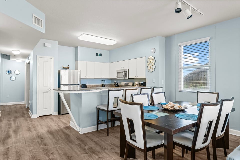 Modern kitchen and dining area with light blue walls and ample seating.