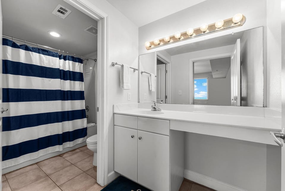 Clean bathroom with a large mirror and striped shower curtain