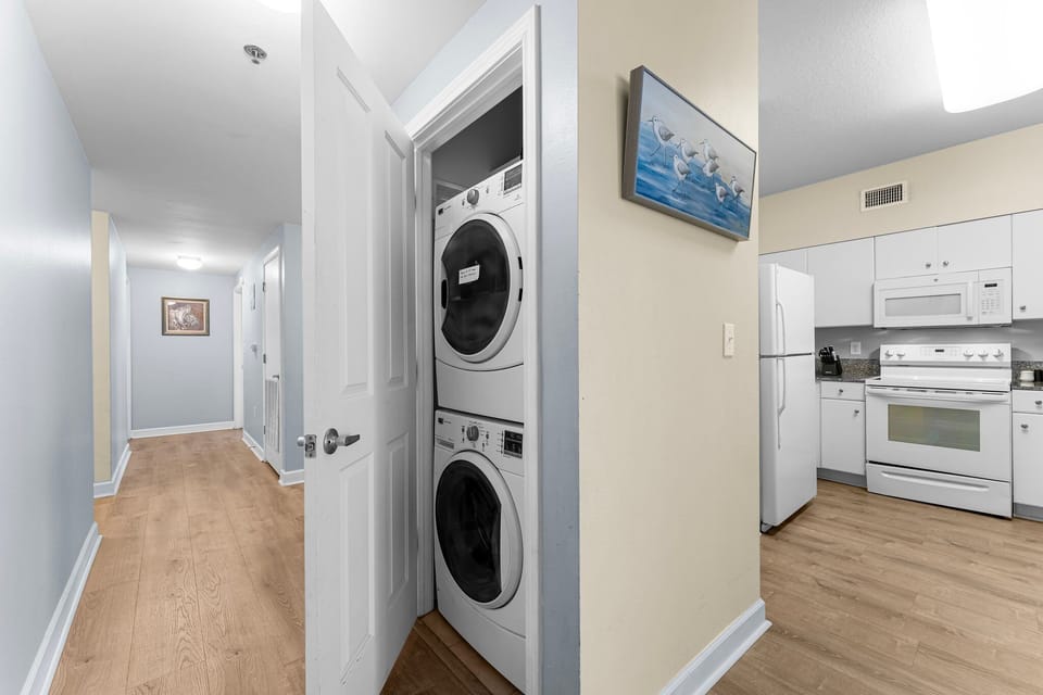 Stacked washer and dryer conveniently located near the kitchen in a modern apartment.