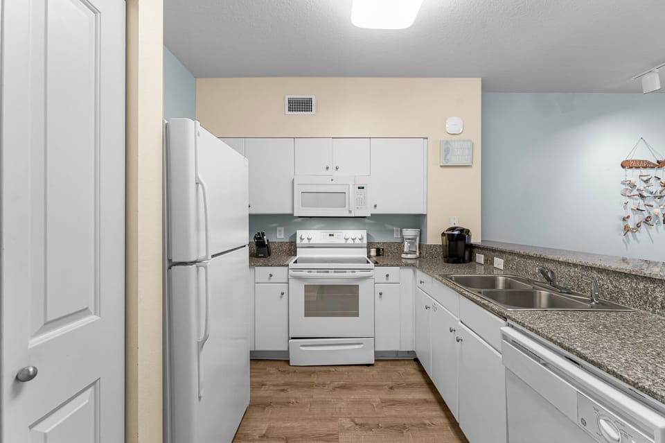 Compact kitchen with white appliances and granite countertops