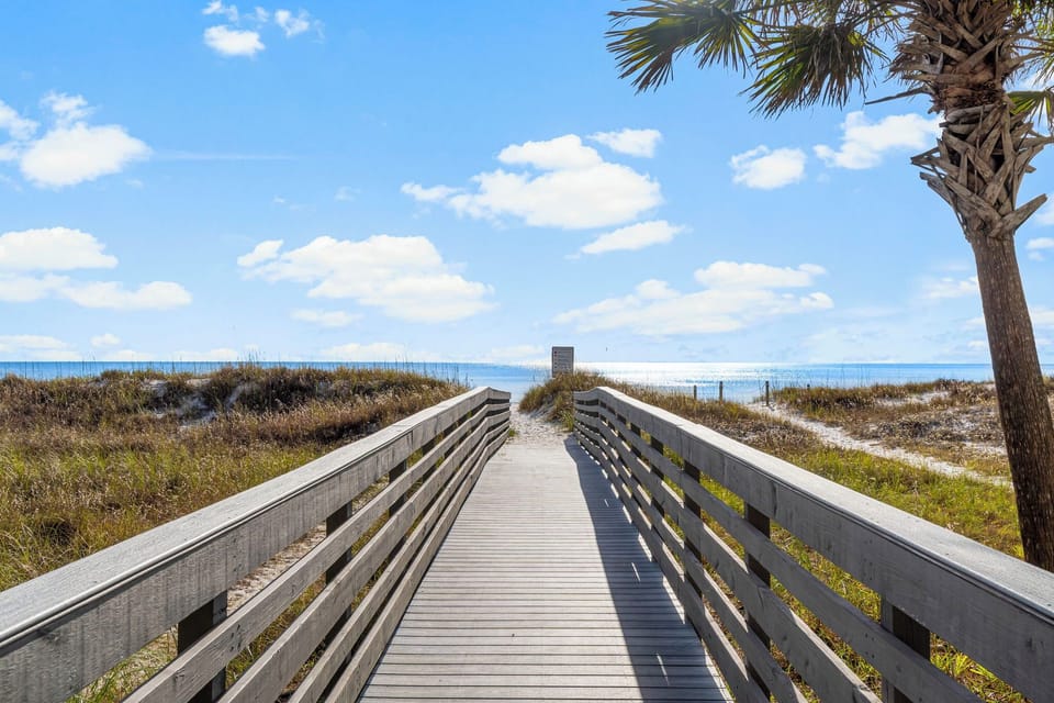 walk along the wooden boardwalk to the beach under a clear sky