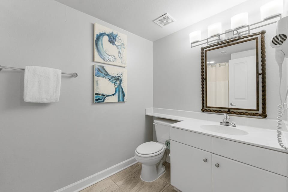 Modern bathroom with white cabinetry and decorative wall art