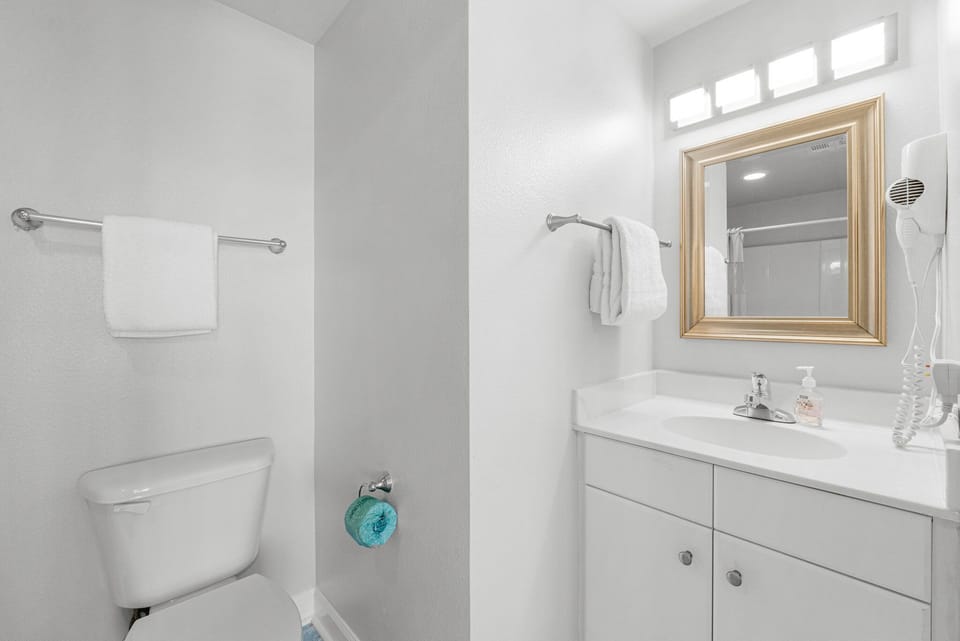 Clean and simple bathroom with a large mirror and ample lighting.