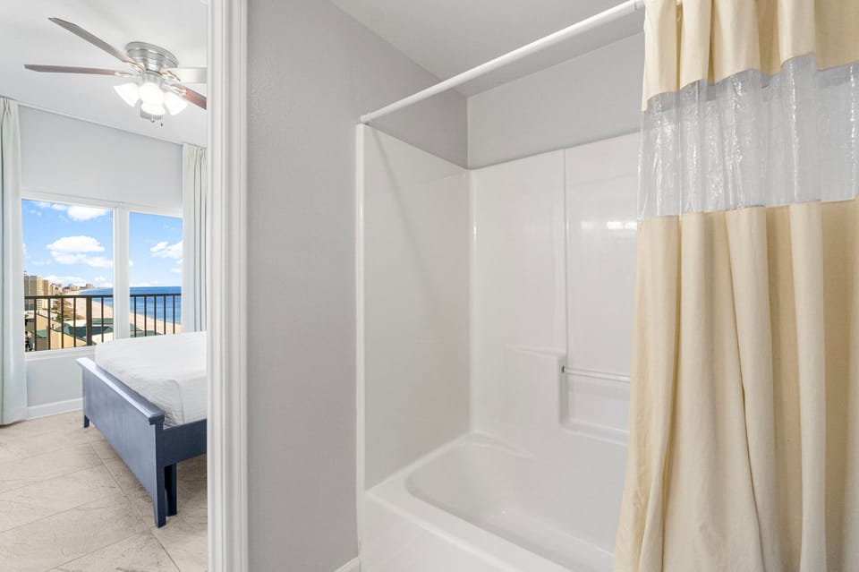 Bright bathroom with a bathtub and a view into the adjacent bedroom.