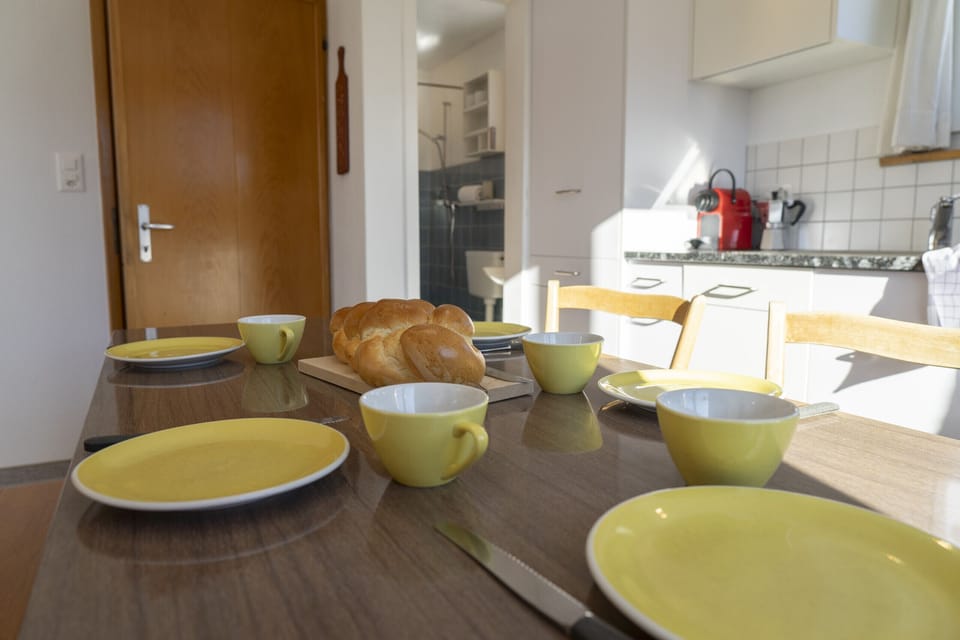 Breakfast table with bread rolls and bright kitchen