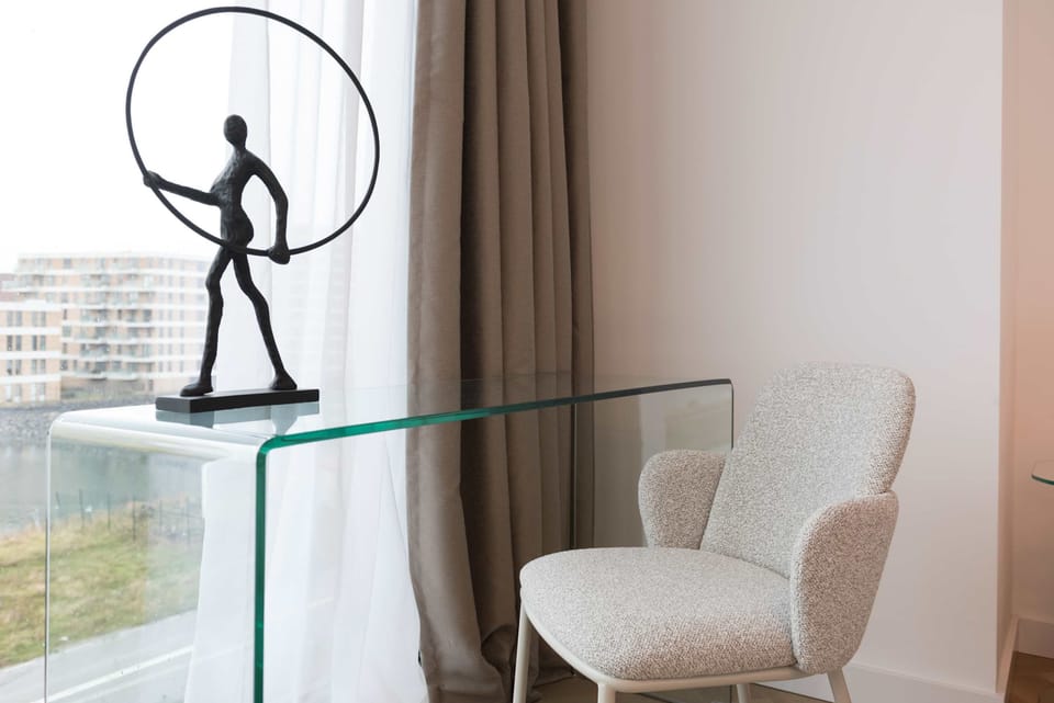 Glass desk with comfortable, soft chair, and a touch of modern art to add some personality to the space
