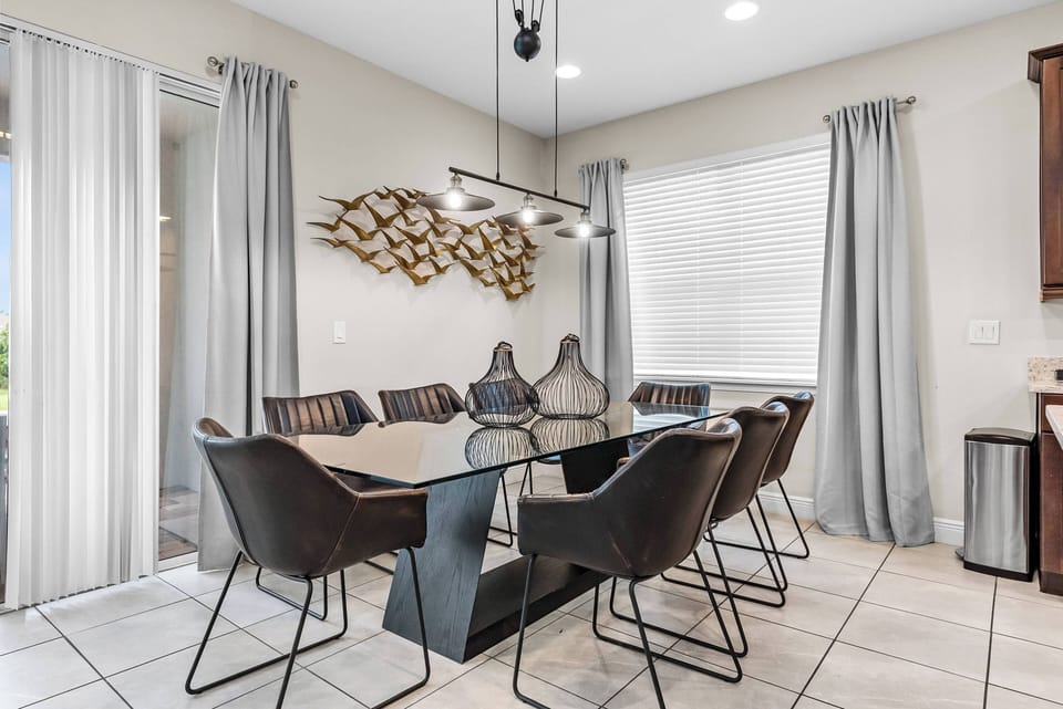 Enjoy a stylish dining area with a sleek glass table and contemporary black chairs, ideal for gatherings. Tall windows with soft curtains let in natural light, creating a warm and inviting atmosphere for you and your guests.