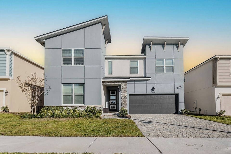 Experience the charm of this contemporary home featuring a striking gray exterior and sleek lines, complemented by a well-kept lawn and stylish stone accents, creating an inviting atmosphere for your next vacation getaway.