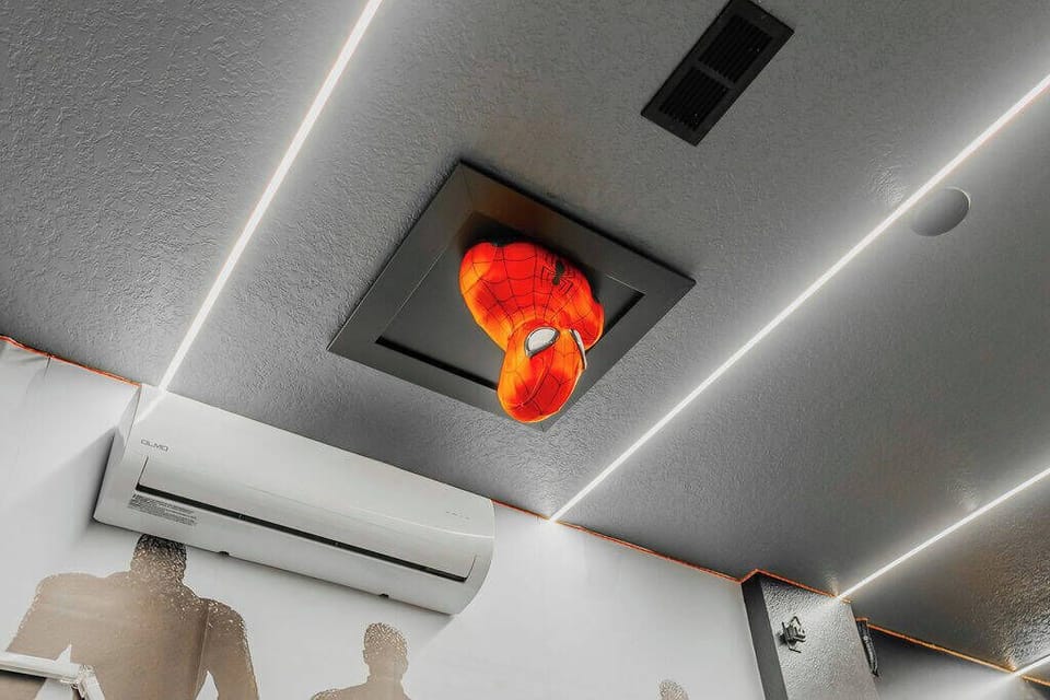 Enjoy the vibrant ceiling decor and modern lighting that create a unique atmosphere. The subtle gray walls and air conditioning unit add to the contemporary vibe, making the space welcoming and inviting for your experience.