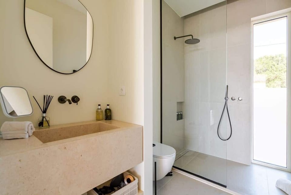 A modern bathroom conveniently located next to Bedroom 3, featuring a spacious walk-in shower, a makeup mirror, and luxury Molton Brown toiletries. Enjoy the convenience of a Dyson hairdryer and sleek, minimalist design for a refreshing experience