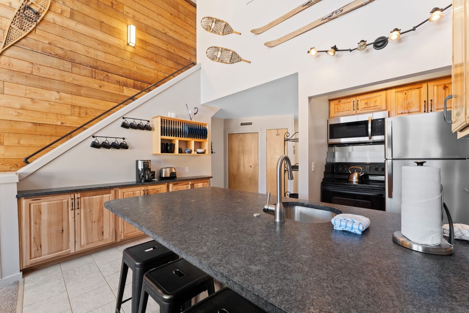 Full kitchen featuring updated stone countertops, stainless steel appliances, and breakfast bar.