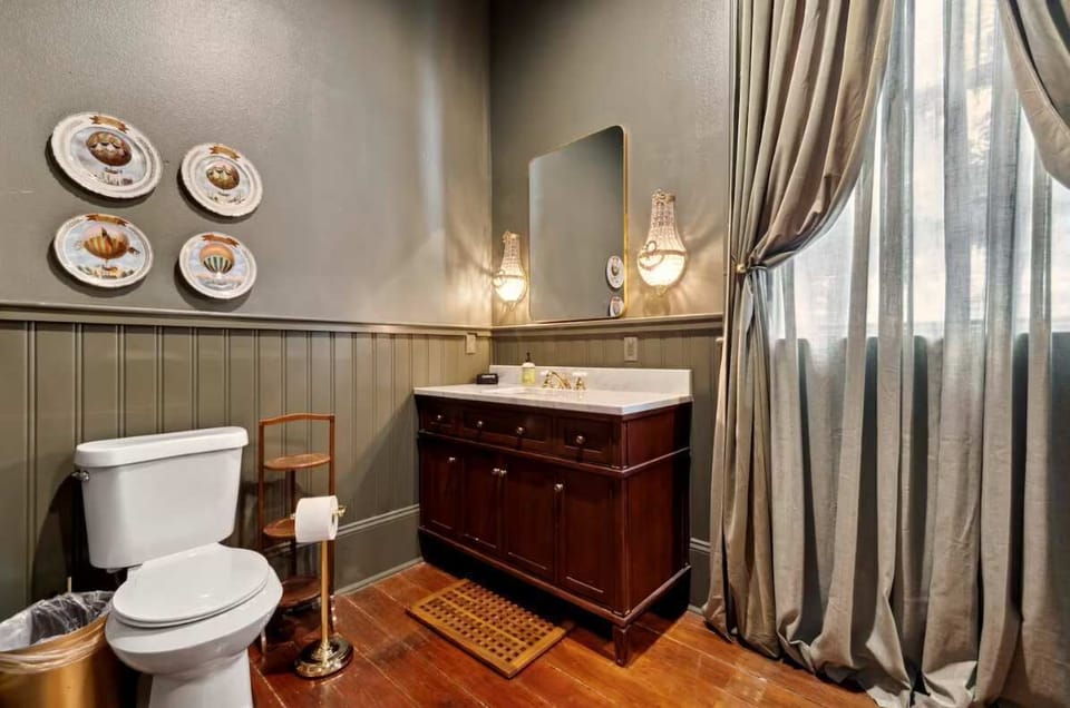 Marble-topped vanity with crystal sconces and beadboard walls; whimsical hot-air-balloon plates add a playful touch.
