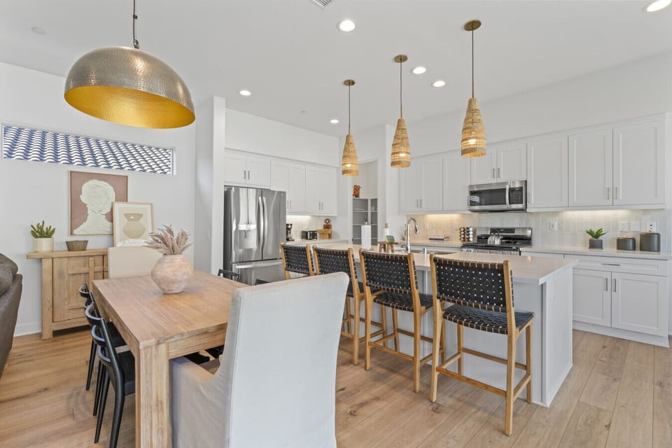 Modern kitchen & dining space w/ large island, bar stools & statement lighting
