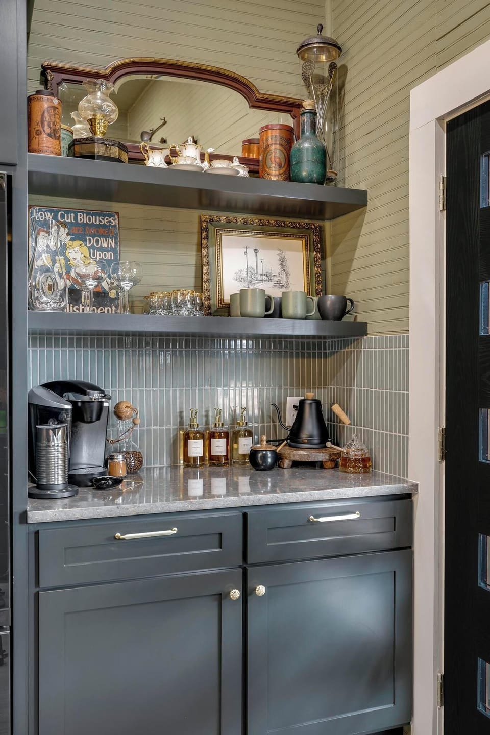 The perfect home coffee bar for your mornings, complete with a coffee maker, frother, kettle, flavoring syrups, teas, coffee pods, honey, cinnamon, and sugar. 