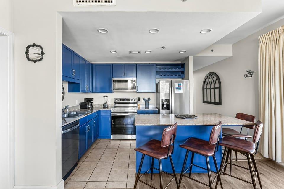 Modern kitchen with blue cabinetry and a breakfast bar with seating.