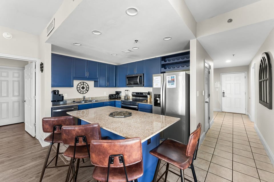 Modern kitchen with blue cabinetry and a large granite island for casual dining.