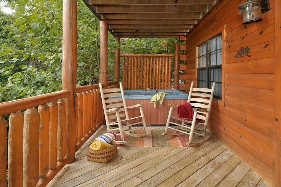 Hot tub and rocking chairs on a covered deck at Kick Back & Relax! A 4 bedroom cabin rental located in Pigeon Forge